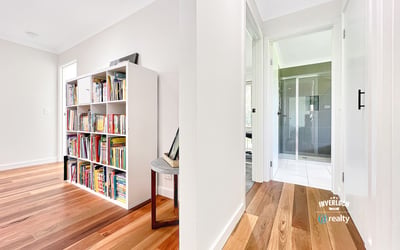 Bright and inviting interior featuring wooden floors, a spacious hallway, and a versatile bookshelf area.