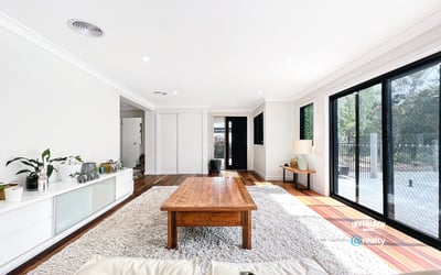 Bright open living space featuring large windows, natural light, and a warm wood coffee table.