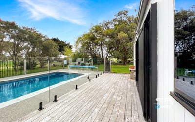 Discover a modern retreat featuring a spacious deck and inviting pool surrounded by lush greenery.