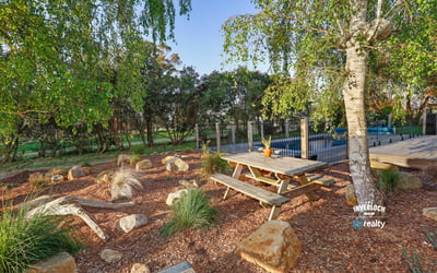 This outdoor space features a picnic area surrounded by native landscaping and a pool in the background.