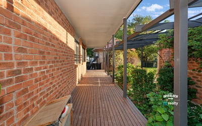 Inviting walkway lined with brick and greenery, leading to a secluded outdoor living space.