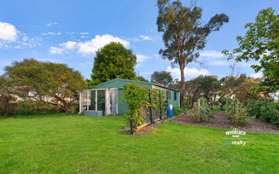 This property features a spacious backyard with greenery and a versatile outbuilding, perfect for various uses.