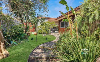Lush landscaped garden with diverse plants and a cozy patio, perfect for outdoor gatherings and relaxation.