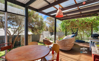 Relax in this inviting outdoor space with a cozy seating area, surrounded by lush greenery.