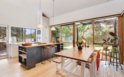 Bright and spacious kitchen with large windows, inviting natural light and views of the landscaped yard.