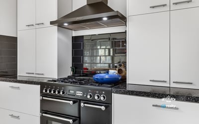 Modern kitchen featuring sleek cabinetry, a gas range, and a striking mirrored backsplash for added depth.