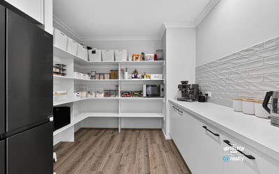 Discover a spacious pantry featuring smart shelving and modern appliances, perfect for organized meal prep.