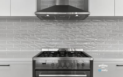 Modern kitchen featuring a stainless steel gas range and sleek gray tile backsplash for optimal cooking experience.