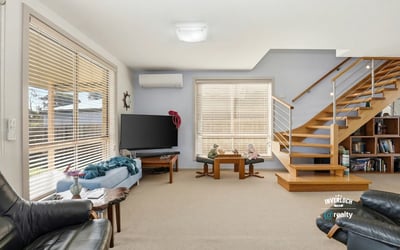 Spacious living area featuring high ceilings, abundant natural light, and modern staircase, ideal for gatherings.