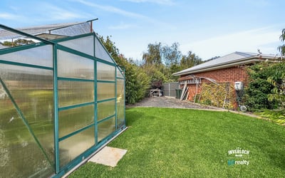 Spacious backyard featuring a functional greenhouse and plenty of room for gardening or outdoor activities.