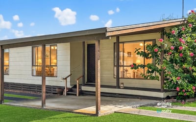 This inviting home features a spacious front porch and lush landscaping, perfect for outdoor relaxation.