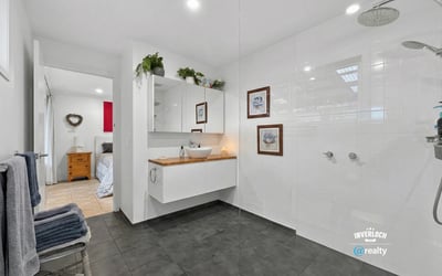 Modern bathroom featuring spacious walk-in shower, dual rainfall showerheads, and sleek cabinetry for organized storage.