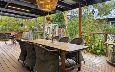 Spacious outdoor deck with ample seating, perfect for entertaining amidst lush greenery and a relaxing atmosphere.