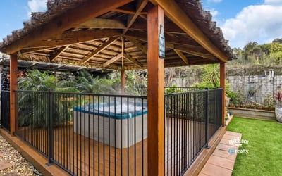 Relax in this private outdoor gazebo featuring a hot tub, surrounded by lush greenery.