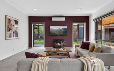 Cozy living room with modern features, featuring a fireplace and large windows overlooking a private outdoor space.