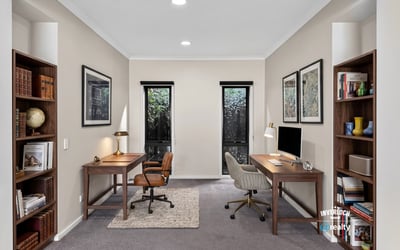 Spacious dual office setup featuring natural light, modern furnishings, and ample shelving for productivity.