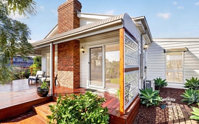 Inviting home features a spacious deck and lush landscaping, perfect for outdoor gatherings and relaxation.
