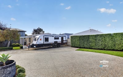 Spacious driveway perfectly accommodates an RV, surrounded by well-maintained landscaping for added privacy and convenience.