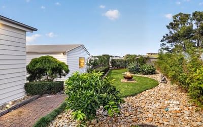 Discover a tranquil outdoor space featuring neat landscaping, unique planting beds, and a cozy fire pit area.