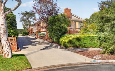 This spacious home features a picturesque landscape, inviting driveway, and ample outdoor space for entertaining.