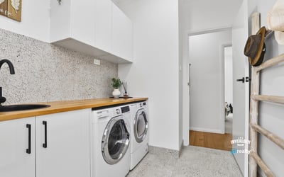 Bright laundry area featuring modern appliances, streamlined cabinetry, and a clean, functional design.