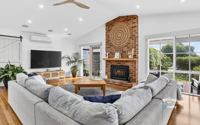 Spacious living area features a cozy fireplace, ample natural light, and direct access to outdoor views.