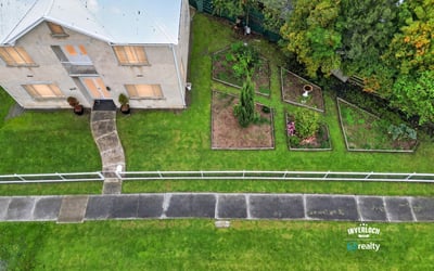 Spacious two-story home with expansive gardens, offering a unique outdoor living experience and plenty of potential.