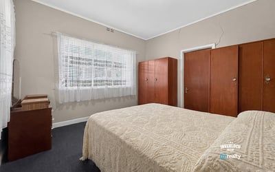 Bright and spacious bedroom featuring built-in wardrobes and ample natural light from large windows.