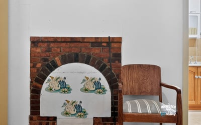 Cozy space featuring a unique fireplace design and inviting wooden chair for relaxation or reading.