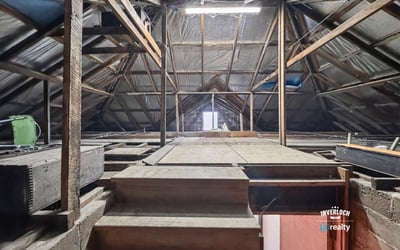 Spacious attic with exposed beams, offering limitless potential for customization or creative use.
