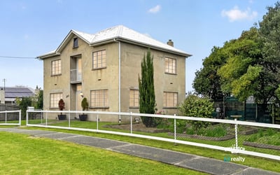 This spacious two-story home features large windows, a manicured lawn, and ample outdoor space for gatherings.