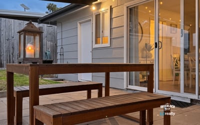 This inviting outdoor space features a wooden dining set and soft lighting, perfect for gatherings.