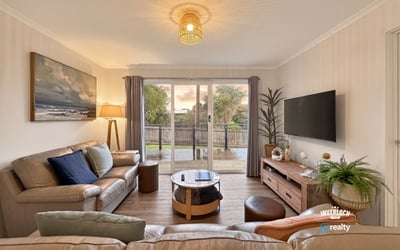 Bright living room with modern furnishings, large window views, and seamless access to an outdoor deck.