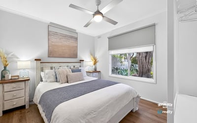 Bright, airy bedroom featuring natural light, modern decor, and a view of lush greenery outside.