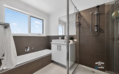 Modern bathroom featuring a glass shower, freestanding tub, and ample natural light from large windows.