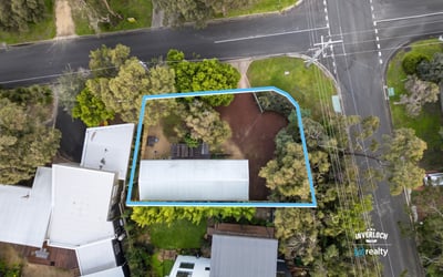 Spacious lot featuring a prime location near a main intersection, surrounded by lush greenery.