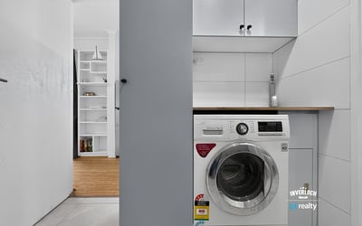 Compact laundry area featuring modern appliances and efficient storage solutions for optimal functionality.