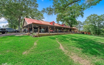 Spacious property featuring a large covered porch, surrounded by lush greenery and scenic views.