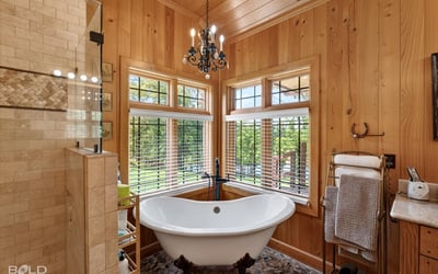 Experience a bright, inviting bathroom featuring a freestanding tub and large windows with scenic views.