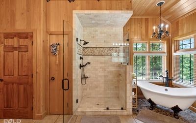 This luxurious bathroom features a spacious walk-in shower and a freestanding tub, surrounded by natural light.