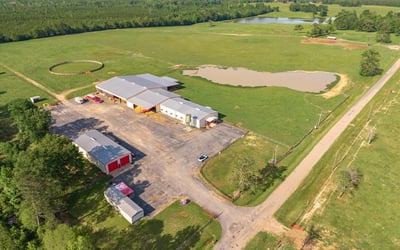 Spacious rural property featuring vast open fields, a pond, and extensive outbuildings for multiple uses.