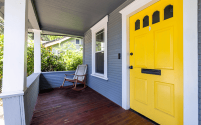 Bright yellow door welcomes you to this inviting porch, perfect for relaxing and enjoying the outdoors.