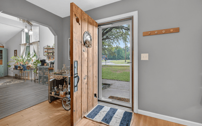 Welcoming entryway featuring a solid wooden door, leading to an inviting, open living space with abundant natural light.