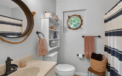 Bright bathroom featuring modern fixtures, a unique round window, and ample storage for convenience.
