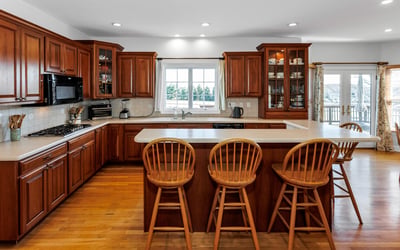 Highlights of the beautiful Kitchen include cherry cabinets, tile backsplash, Island with breakfast bar, hardwood flooring, and recessed lighting.