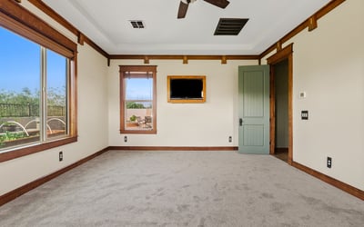 Alternate view of the primary bedroom highlighting tray ceilings, natural light, and refined wood accents. A comfortable and elegant space in this Phoenix home.