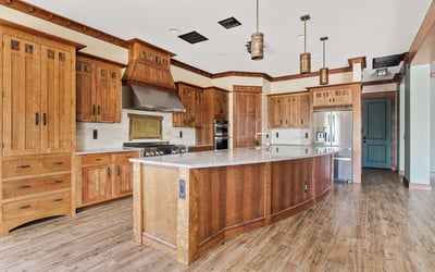 Gourmet kitchen featuring an oversized island, custom wood cabinetry, stone countertops, and professional-grade appliances. A standout space for cooking and entertaining.