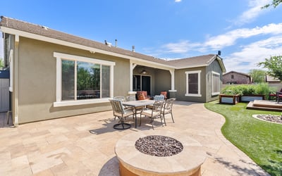 This expansive paver backyard offers a perfect blend of function and fun with its built-in BBQ, firepit, and seating for gatherings under the Arizona sky.