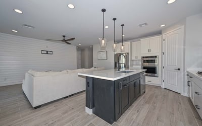 The kitchen offers unobstructed views into the great room, featuring pendant lighting, sleek finishes, and plenty of prep space on the oversized island.