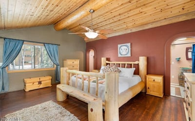 Spacious primary bedroom showcasing vaulted ceilings, rustic log craftsmanship, and an open loft-style overlook that adds character and architectural interest.